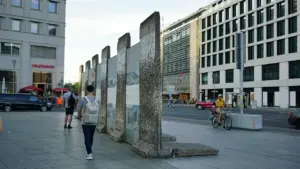 Ein Teil der Berliner Mauer mit Passanten auf einem Gehweg in Berlin.