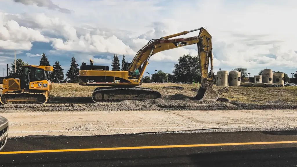 Gelbe Bagger bei Erdarbeiten an einer neu angelegten Baustelle am Straßenrand.