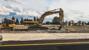 Gelbe Bagger bei Erdarbeiten an einer neu angelegten Baustelle am Straßenrand.