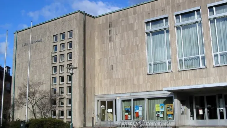 Die steinerne Fassade des Justus-Liebig-Hauses mit großen Fenstern und dem Eingang der Volkshochschule.