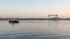 Ein kleines Schiff fährt bei Sonnenuntergang durch die ruhige Kieler Förde