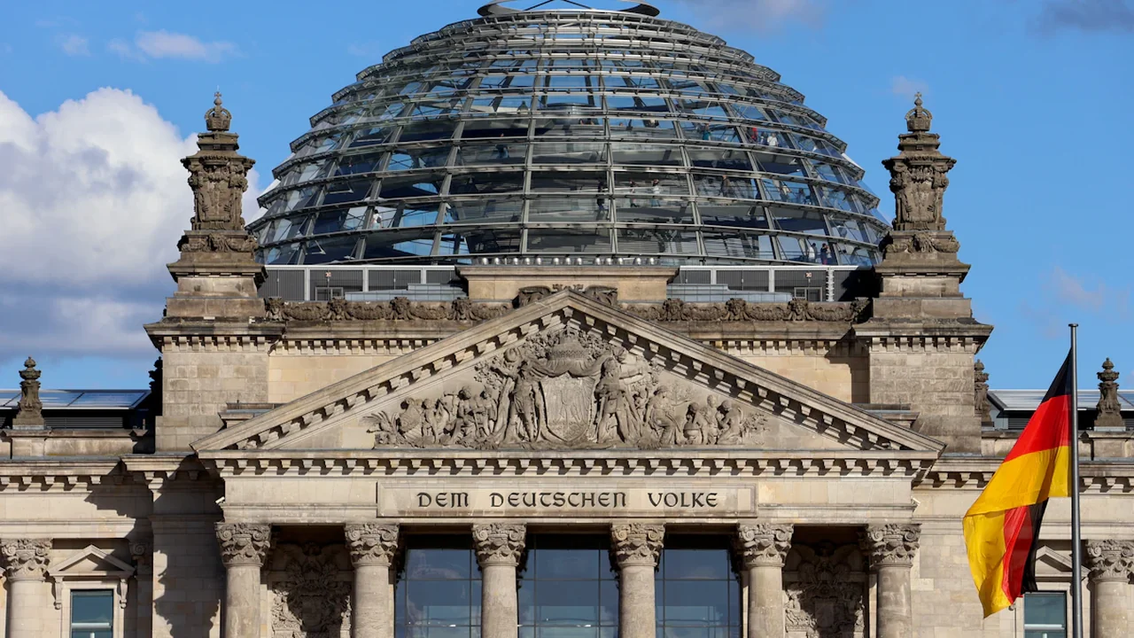 Das Reichstagsgebäude mit Glaskuppel und wehender deutscher Flagge in Berlin.