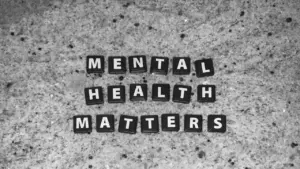 Buchstabenwürfel mit der Aufschrift Mental Health Matters auf einem strukturierten, grauen Untergrund.