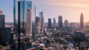 Die Frankfurter Skyline mit Bankentürmen unter einem hellen, wolkigen Himmel am Tag.