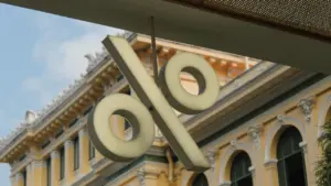 Ein großes Prozentzeichen hängt vor einem historischen Bankgebäude als Symbol für die Zinspolitik.