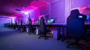 Ein moderner Gaming-Raum mit zahlreichen Computern und Stühlen in stimmungsvollem violetten Licht in Deutschland.