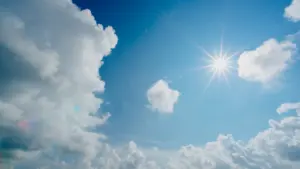 Strahlend blauer Himmel mit weißen Schönwetterwolken und intensiver Sonneneinstrahlung an einem heißen Tag.