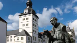 Statue vor einem historischen Gebäude in Paderborn unter blauem Himmel.