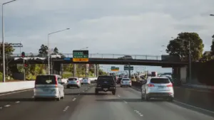 Autobahn mit Autos bei Tageslicht und Hinweisschildern über der Fahrbahn.