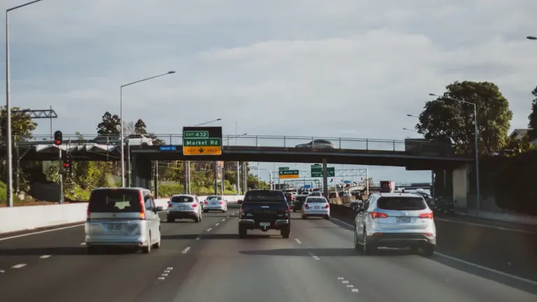 Autobahn mit Autos bei Tageslicht und Hinweisschildern über der Fahrbahn.