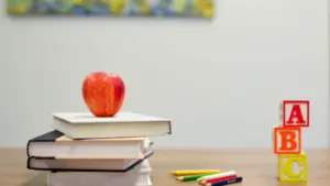 Ein roter Apfel auf einem Bücherstapel mit ABC-Würfeln als Schulstart-Symbolik.