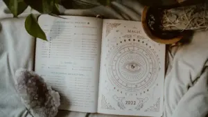 Offenes Buch mit astrologischen Symbolen und Mondphasen auf einem bequemen Bett.
