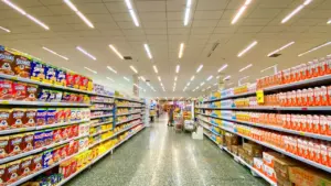 Ein langer, heller Supermarktgang mit gut gefüllten Regalen an beiden Seiten.