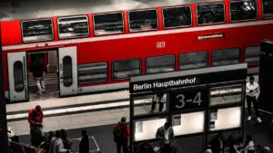 Ein roter Regionalzug der Deutschen Bahn fährt an einem grauen Tag in den Bahnhof.