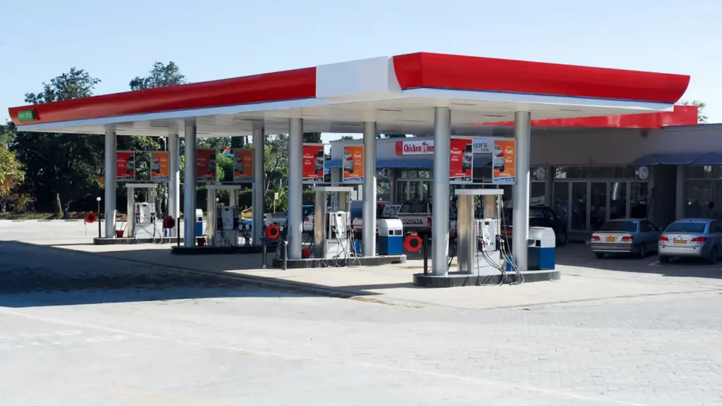 Eine moderne Tankstelle bei Tageslicht mit Zapfsäulen und geparkten Autos an der Straße.