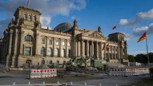 Das Berliner Reichstagsgebäude mit deutscher Flagge vor einem bewölkten Himmel.