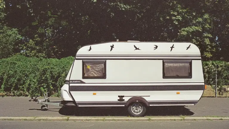 Weißer Wohnwagen parkt an einer Straße, ideal für Berichte über Camping-Fehlkäufe.