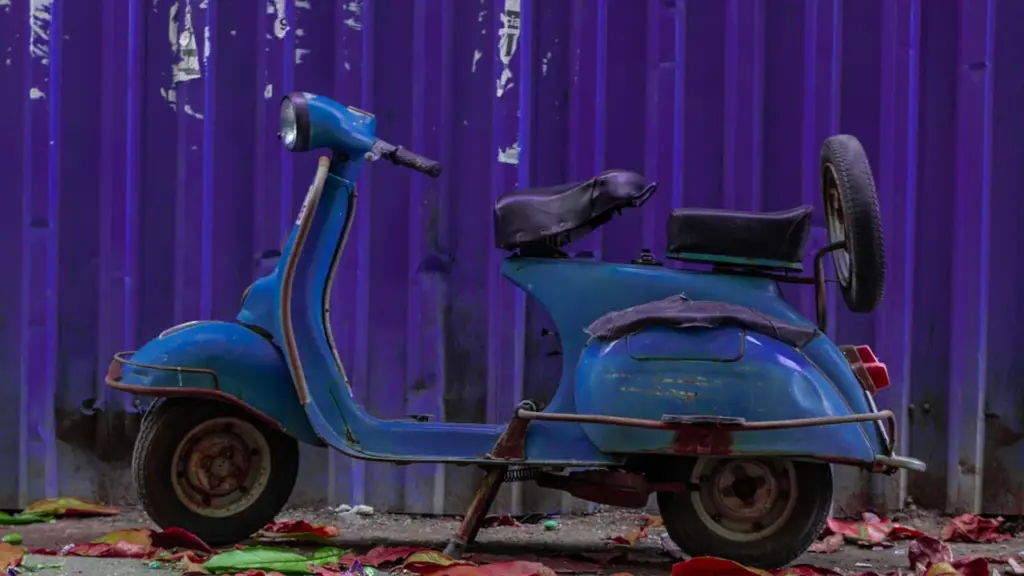 Ein blauer Elektroroller geparkt vor einer leuchtend violetten Wand im städtischen Raum.