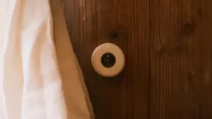 Ein weißer Keramik-Türknauf an einer hölzernen Innentür in einer Wohnumgebung.