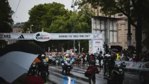 Ein startender Marathon bei Regenwetter mit Zuschauern und Polizeiabsperrung in einer Stadt.