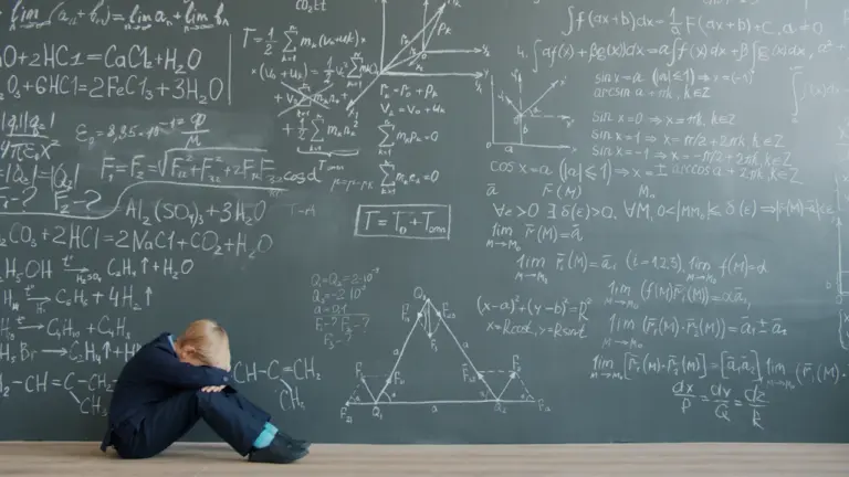 Ein Kind sitzt verzweifelt vor einer großen Schultafel voller komplexer mathematischer Formeln.