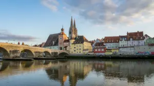 Blick auf die Regensburger Altstadt und den Dom am Ufer der Donau bei Sonnenuntergang.