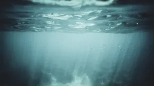Tiefes, geheimnisvolles Wasser unter der Meeresoberfläche mit sanftem, einfallendem Licht von oben.