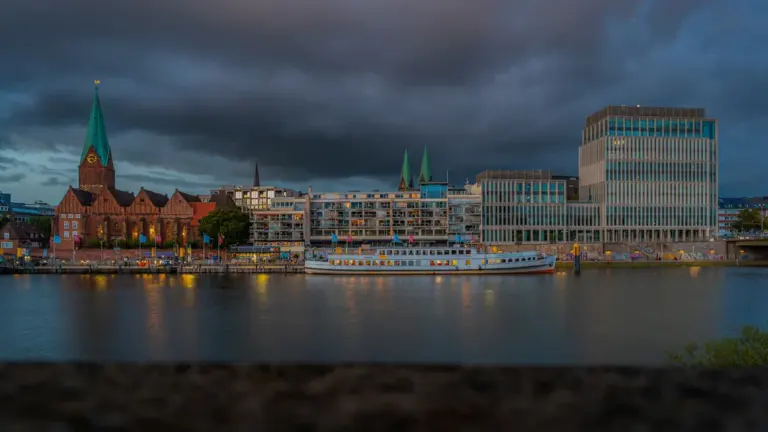 Ein Flussboot liegt bei bewölktem Himmel am Ufer der Bremer Innenstadt.