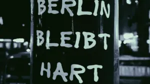 Schwarz-Weiß-Foto eines an einem Mast befestigten Schildes mit der Aufschrift Berlin bleibt hart.
