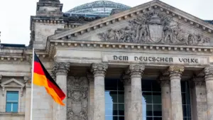 Das Reichstagsgebäude mit der wehenden deutschen Flagge in Berlin bei Tageslicht.
