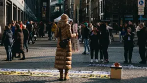 Eine Person hält ein Protestschild auf einem belebten Leipziger Marktplatz am Tag.