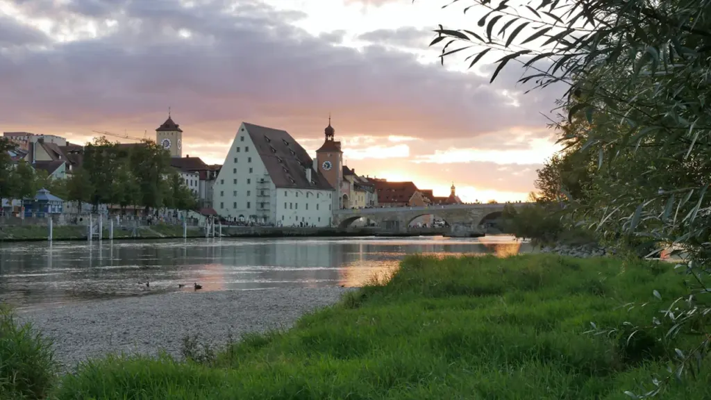 Blick auf die Steinerne Brücke und den historischen Salzstadel in Regensburg am Abend.
